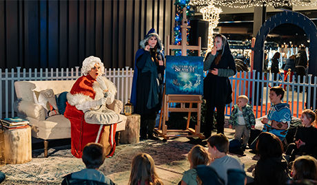 kids are watching a theatre with mrs claus and two witches at the Enchant Christmas village