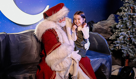 santa hugging a little girl and posing at the Enchant Christmas village