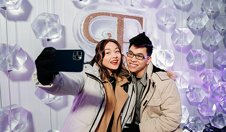 couple posing in the ice bar in front of enchant christmas logo
