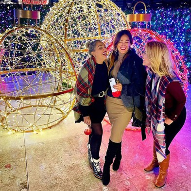 three ladies laughing and posing in front of light balls