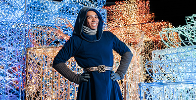 VIP Elf smiling in front of the lights at the Enchant Christmas Village
